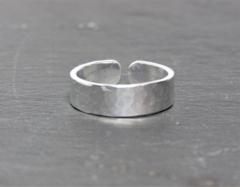 May include: A silver hammered adjustable ring. The ring is made of metal and has a smooth, hammered finish.