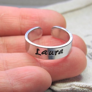 以下が含まれることがあります： 「Laura」と刻まれたシルバーの調節可能なリングです。