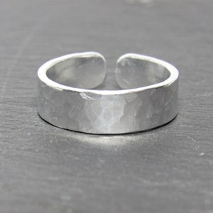 May include: A silver hammered adjustable ring. The ring is made of metal and has a smooth, polished finish.
