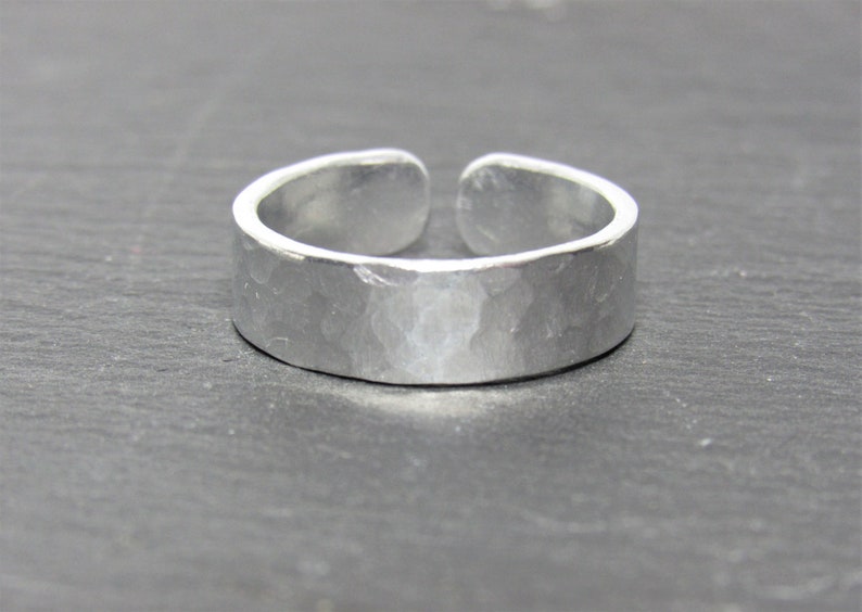 May include: A silver hammered adjustable ring. The ring is made of metal and has a smooth, polished finish.