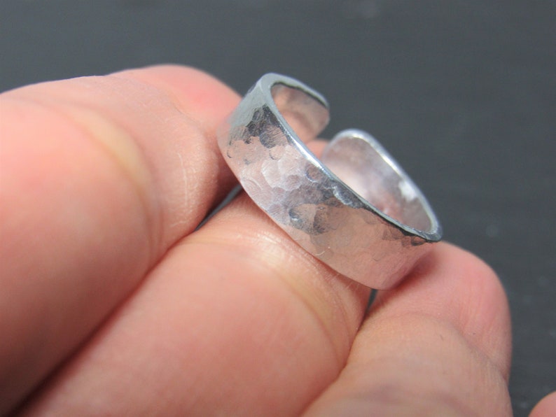 May include: A silver hammered ring with an open design. The ring is made of metal and has a textured surface.