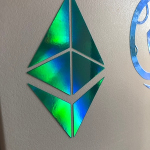 May include: A holographic green and blue Ethereum cryptocurrency logo sticker.