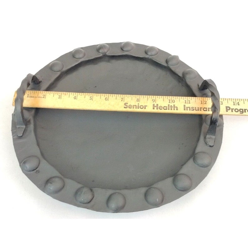 Puede incluir: Una bandeja de metal negro con dos asas y un acabado martillado. La bandeja tiene un di&aacute;metro de aproximadamente 28 cm y un anillo de puntos de metal elevados alrededor del borde.