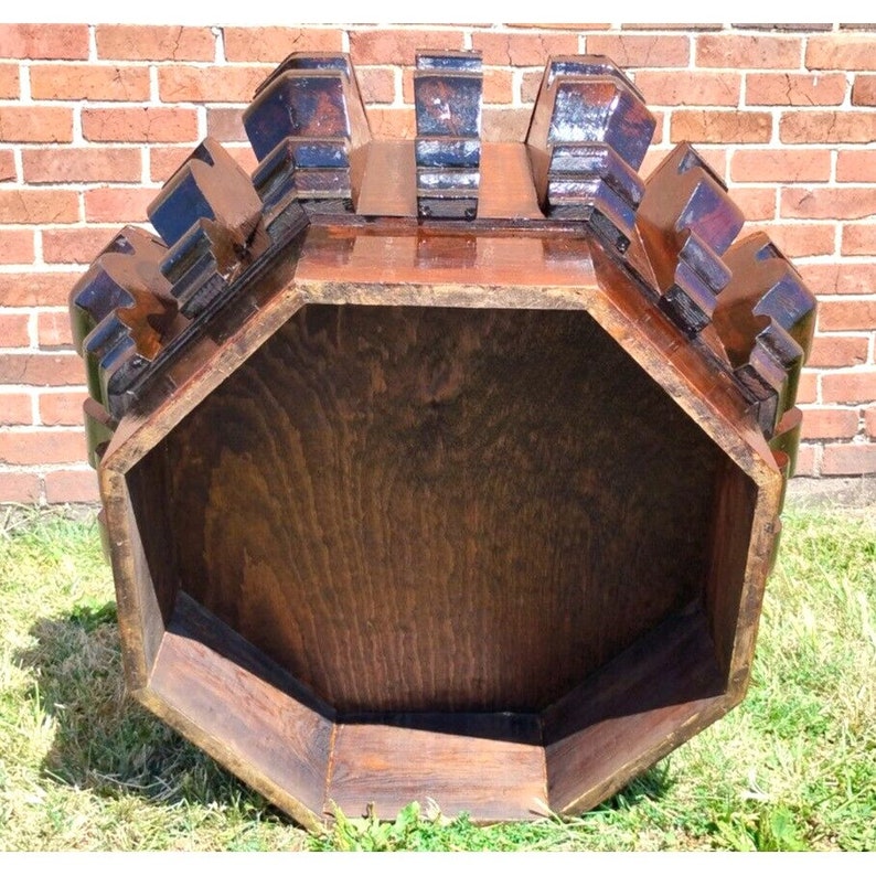 Puede incluir: Una mesa octogonal de madera marr&oacute;n oscuro con una parte superior tallada decorativa. La mesa est&aacute; vac&iacute;a y tiene una superficie lisa y pulida.