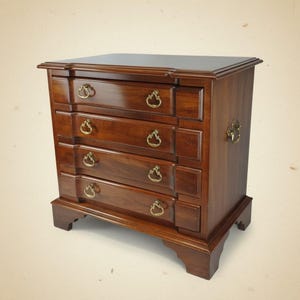 May include: A wooden nightstand with four drawers and brass hardware. The nightstand is a dark brown color with a rectangular shape and a flat top. The drawers have decorative pulls.
