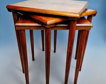 May include: A set of three nesting tables with a wood grain finish. The tables are made of solid wood and have a simple, mid-century modern design.