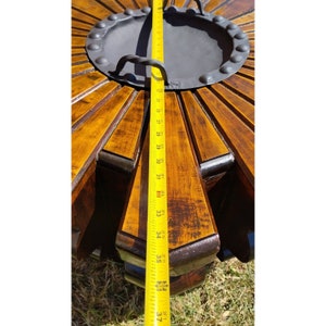 Puede incluir: Una tapa de mesa de madera con un dise&ntilde;o circular y una pieza central de metal. La tapa de la mesa est&aacute; te&ntilde;ida de un color marr&oacute;n oscuro y tiene un aspecto desgastado. Una cinta m&eacute;trica se coloca a lo largo del borde de la tapa de la mesa, mostrando una medida de 94 cm.