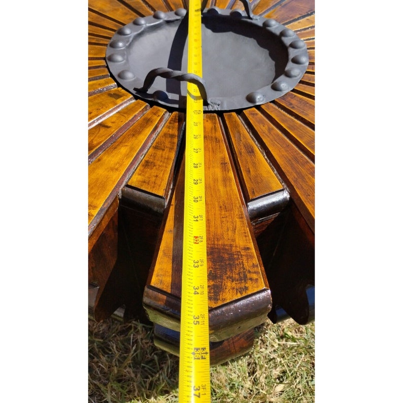 Puede incluir: Una tapa de mesa de madera con un dise&ntilde;o circular y una pieza central de metal. La tapa de la mesa est&aacute; te&ntilde;ida de un color marr&oacute;n oscuro y tiene un aspecto desgastado. Una cinta m&eacute;trica se coloca a lo largo del borde de la tapa de la mesa, mostrando una medida de 94 cm.