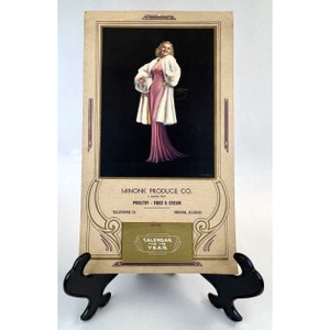 May include: Vintage calendar featuring a woman in a pink dress and white fur coat. The calendar is for Minonk Produce Co. and advertises poultry, eggs, and cream. The text on the calendar reads "Calendar for the Year".