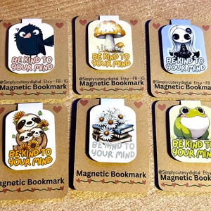May include: Six different magnetic bookmarks with various designs. Each bookmark features a cute illustration and the text "Be Kind to Your Mind". The designs include a black bird, a mushroom, a girl with black hair, a sloth family, a stack of books with daisies, and a green frog.