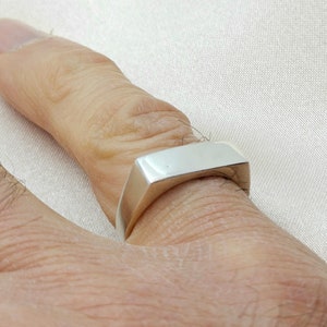 Peut inclure: Une bague carrée en argent avec un dessus plat et des bords arrondis.