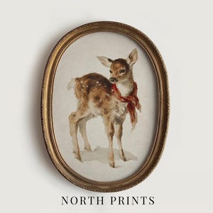 May include: An oval framed print featuring a watercolor painting of a fawn with brown fur and white spots, wearing a red scarf. The frame is gold-colored. The text "NORTH PRINTS" is at the bottom.