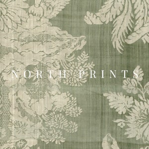 May include: A green fabric with a white floral pattern. The fabric has a subtle sheen and a textured surface. The text "NORTH PRINTS" is printed in white on the fabric.