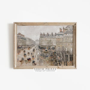 May include: A framed vintage print of a city street scene. The artwork depicts a rainy day with horse-drawn carriages and pedestrians on a wide boulevard lined with buildings. The print has a neutral colour palette with a distressed, antique aesthetic. The text "NORTH PRINTS vintage art collective" is visible.