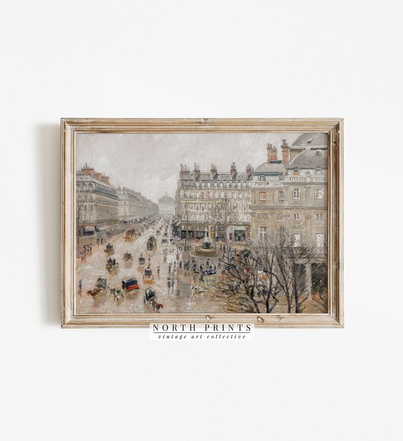 May include: A framed vintage print of a city street scene. The artwork depicts a rainy day with horse-drawn carriages and pedestrians on a wide boulevard lined with buildings. The print has a neutral colour palette with a distressed, antique aesthetic. The text "NORTH PRINTS vintage art collective" is visible.