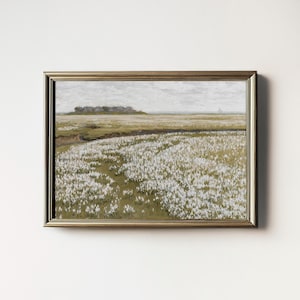 May include: A framed painting depicting a field of white flowers in a landscape setting. The flowers are in the foreground, with a distant view of a small town or village in the background. The sky is a light gray, and the overall tone of the painting is serene and peaceful.