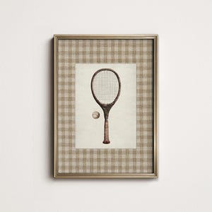 May include: Framed vintage tennis print featuring a detailed illustration of a tennis racket and ball. The artwork is set against a cream-colored background and framed with a gold border and a checkered pattern.
