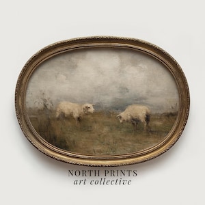 Puede incluir: Una impresión enmarcada de forma ovalada que presenta una escena pastoral con dos ovejas pastando en un campo bajo un cielo nublado. El marco es dorado con detalles ornamentados. El texto "NORTH PRINTS art collective" está en la parte inferior.