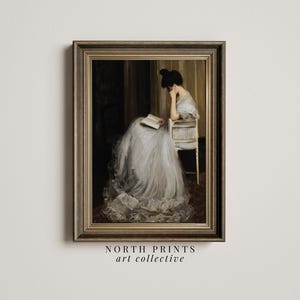 May include: A framed painting of a woman in a white dress sitting in a chair and reading a book. The painting is set in a room with a dark background and a light-colored wall.
