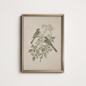 May include: A framed print featuring two birds perched on a flowering branch. The artwork is rendered in shades of green on a beige background, with a gold-colored frame. The birds and floral elements are detailed, creating a vintage aesthetic.