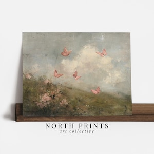 May include: A framed art print featuring a pastel landscape with pink butterflies fluttering in a cloudy sky. The artwork has a vintage aesthetic, with a soft color palette of greens, blues, and pinks. The text "NORTH PRINTS art collective" is at the bottom.