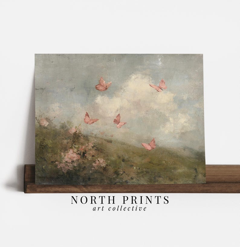 May include: A framed art print featuring a pastel landscape with pink butterflies fluttering in a cloudy sky. The artwork has a vintage aesthetic, with a soft color palette of greens, blues, and pinks. The text "NORTH PRINTS art collective" is at the bottom.