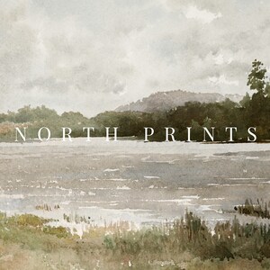 Puede incluir: Una pintura de acuarela de un lago con una ladera boscosa en el fondo. El cielo est&aacute; nublado y gris. El texto "NORTH PRINTS" est&aacute; impreso en blanco en el medio de la imagen.