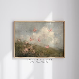 May include: A framed art print featuring a landscape with pink butterflies in flight. The artwork has a soft, painterly style with a cloudy sky and a hint of green foliage. The text "NORTH PRINTS art collective" is at the bottom.