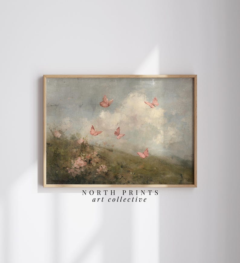 May include: A framed art print featuring a landscape with pink butterflies in flight. The artwork has a soft, painterly style with a cloudy sky and a hint of green foliage. The text "NORTH PRINTS art collective" is at the bottom.