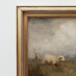 K&ouml;nnte beinhalten: Gerahmtes Landschaftsgem&auml;lde mit einem Schaf auf einer Wiese. Das Kunstwerk hat eine ged&auml;mpfte Farbpalette mit Beige-, Braun- und Graut&ouml;nen. Der goldfarbene Rahmen hat ein antikes Finish.