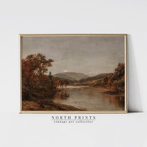 May include: A vintage painting of a river scene with trees and mountains in the background. The sky is a light gray, and the water is a calm blue. The trees are a mix of green and brown, and the mountains are a dark gray. The painting is framed in a simple wooden frame.