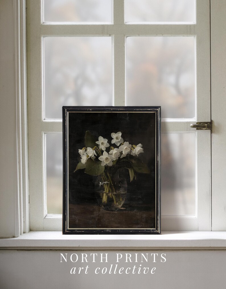 May include: A black framed print of a still life featuring a bouquet of white flowers in a clear glass vase on a dark background. The print is titled "NORTH PRINTS art collective".