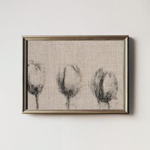 May include: A framed black and white abstract art print of three stylized flower shapes on a beige linen background.