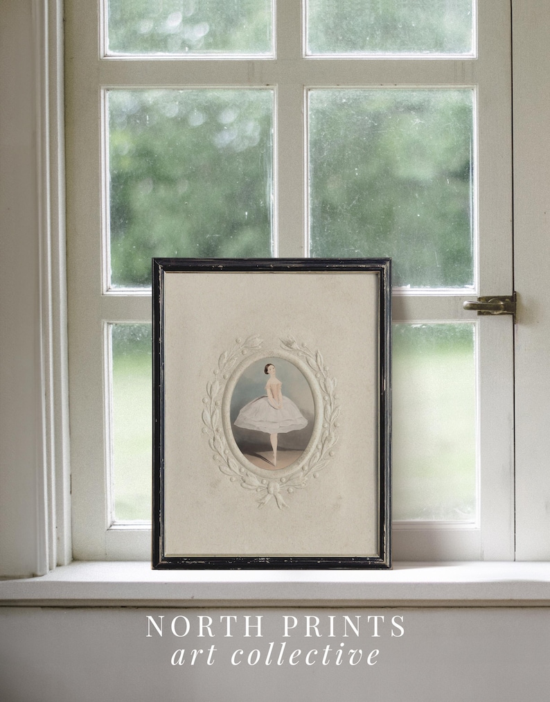 May include: A framed black and white illustration of a ballerina in a white tutu, standing on one leg with her arms outstretched. The illustration is surrounded by a decorative white frame with a floral design. The frame is hanging on a white wall.
