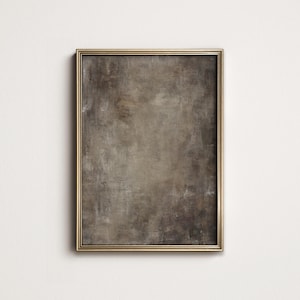 May include: A rectangular framed artwork with a textured, abstract design in shades of brown and gray. The frame is a thin, gold color, and the artwork is mounted on a white wall.