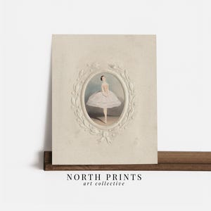 May include: A vintage print of a ballerina in a white tutu, framed with a decorative white border. The print is on a cream-colored background.