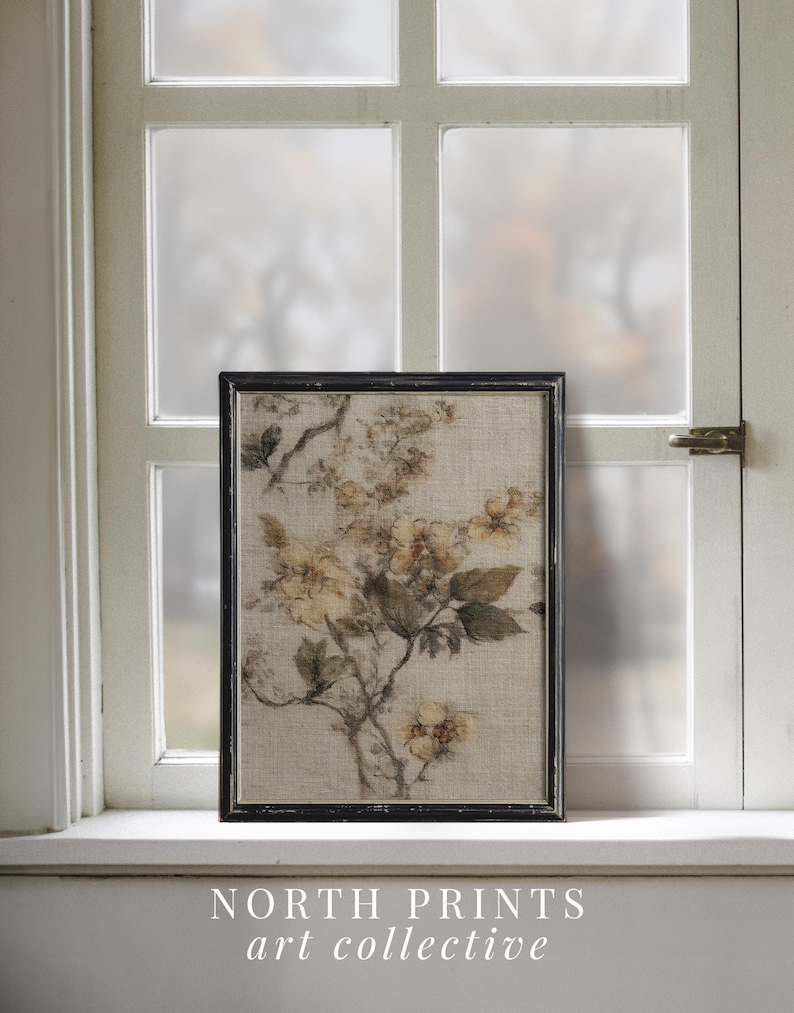 Op de afbeelding: Een ingelijste bloemenprint met een tak met gele bloemen en groene bladeren. Het kunstwerk staat tegen een neutrale achtergrond en is ingelijst in een zwart, rechthoekig frame. De tekst "NORTH PRINTS art collective" staat onderaan.