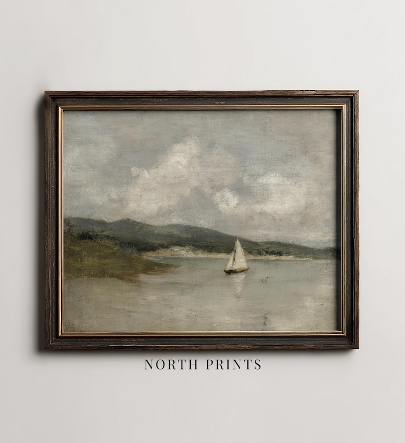 K&ouml;nnte beinhalten: Gerahmtes Vintage-Landschaftsgem&auml;lde mit einem Segelboot auf einem ruhigen See. Das Kunstwerk hat eine ged&auml;mpfte Farbpalette aus Grau, Gr&uuml;n und Braun. Der Rahmen ist dunkelbraun, und der Text "NORTH PRINTS" befindet sich unten.