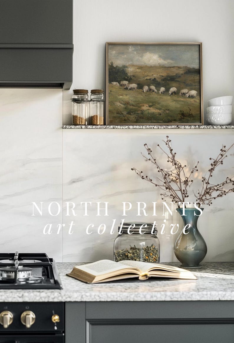 K&ouml;nnte beinhalten: K&uuml;chenszene mit Landschaftsbild von Schafen. Ein Glas, eine Vase mit Zweigen und ein offenes Buch liegen auf der Arbeitsplatte. Der Text "NORTH PRINTS art collective" ist zu sehen. Neutrale Farbgebung.