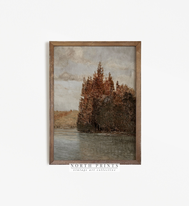 May include: A vintage landscape painting of a lake with trees on the shore. The trees are a mix of green and brown, and the lake is a calm blue. The sky is a light blue with some clouds. The painting is framed in a brown wood frame.