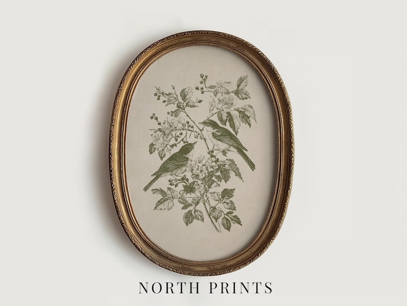 May include: An oval framed print featuring two green birds perched on a flowering branch. The artwork is set against a beige background and enclosed in a gold-colored frame. The text "NORTH PRINTS" is at the bottom.