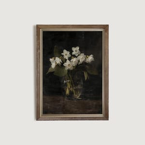 May include: A framed painting of a bouquet of white flowers in a glass vase. The flowers are arranged in a dark background, creating a dramatic and elegant composition.