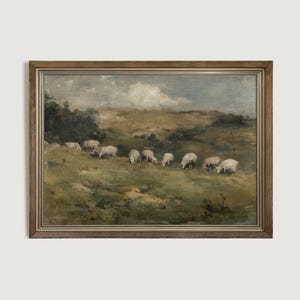 K&ouml;nnte beinhalten: Gerahmtes Gem&auml;lde im antiken Stil, das Schafe zeigt, die auf einem grasbewachsenen H&uuml;gel grasen. Das Kunstwerk verwendet eine ged&auml;mpfte Farbpalette aus Gr&uuml;n-, Braun- und Blaut&ouml;nen, mit einem bew&ouml;lkten Himmel und einem Holzrahmen.