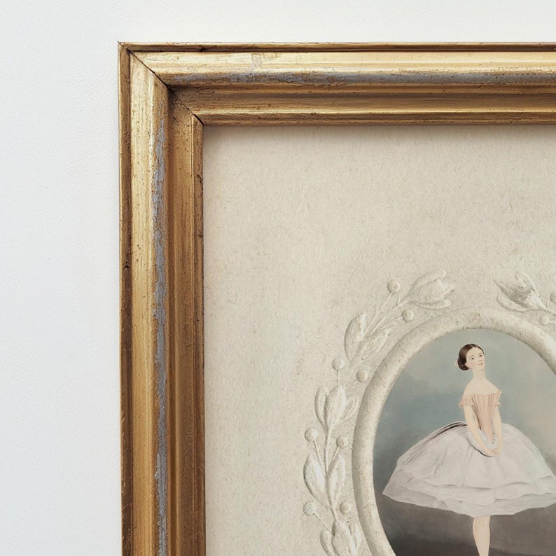 May include: A framed portrait of a ballerina in a white tutu and pink bodice. The frame is gold with a white mat and a decorative white floral design around the portrait.
