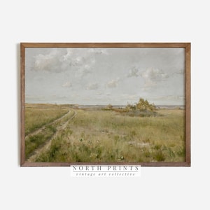 May include: A vintage landscape painting depicting a dirt road leading through a grassy field towards a body of water. The sky is a light blue with white clouds. The painting is framed in a brown wood frame.
