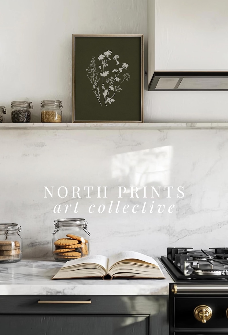 May include: A framed botanical print with white floral illustrations on a dark green background hangs above a countertop. Jars of ingredients and an open book with cookies are on the counter. The text "NORTH PRINTS art collective" is visible.