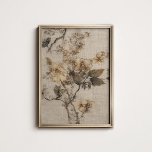 Op de afbeelding: Een ingelijste bloemenprint met een botanische illustratie van gele en bruine bloemen en bladeren. Het kunstwerk is geplaatst tegen een neutrale achtergrond en omlijst in een goudkleurige lijst. De print heeft een vintage esthetiek.