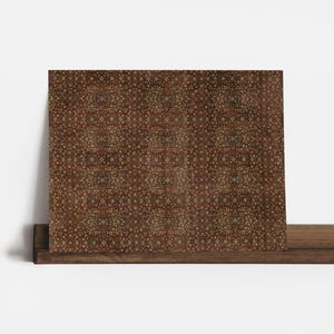 May include: A rectangular decorative panel featuring a repeating pattern of small, circular shapes in shades of brown, tan, and red. The panel is displayed on a wooden shelf against a white background. The pattern has a symmetrical design.