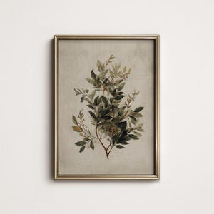 May include: A framed botanical print with a watercolour illustration of leafy branches in green and brown hues. The artwork is set against a neutral backdrop and framed in a gold-coloured metal frame, suitable for home decor.