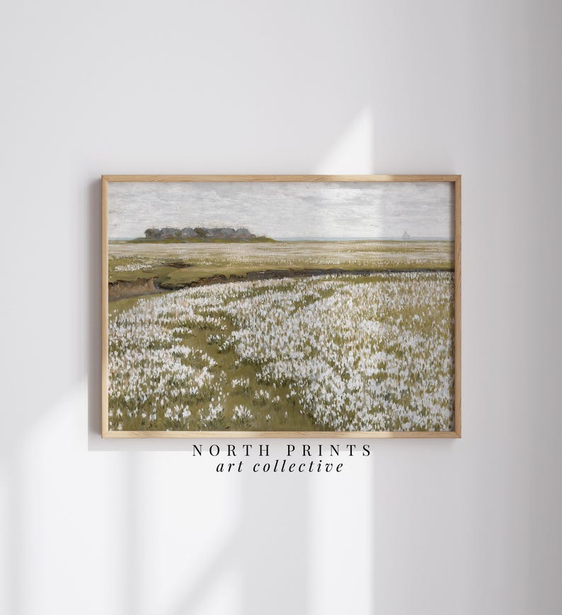 May include: A framed print of a landscape painting depicting a field of white flowers with a distant view of a small town. The painting is in a light brown frame and has a white background.